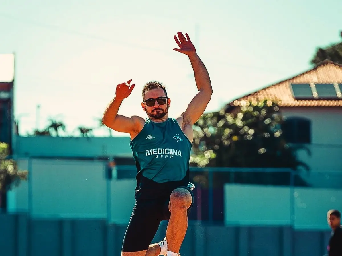Atleta no ar durante um salto na pista de atletismo
